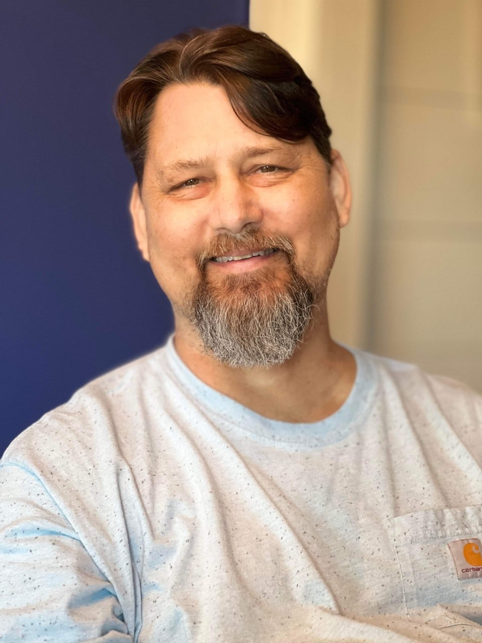 Cliff Arnold, a man between the age of 50-65. Medium to short dark hair and a beard. Wearing a plain white tshirt.